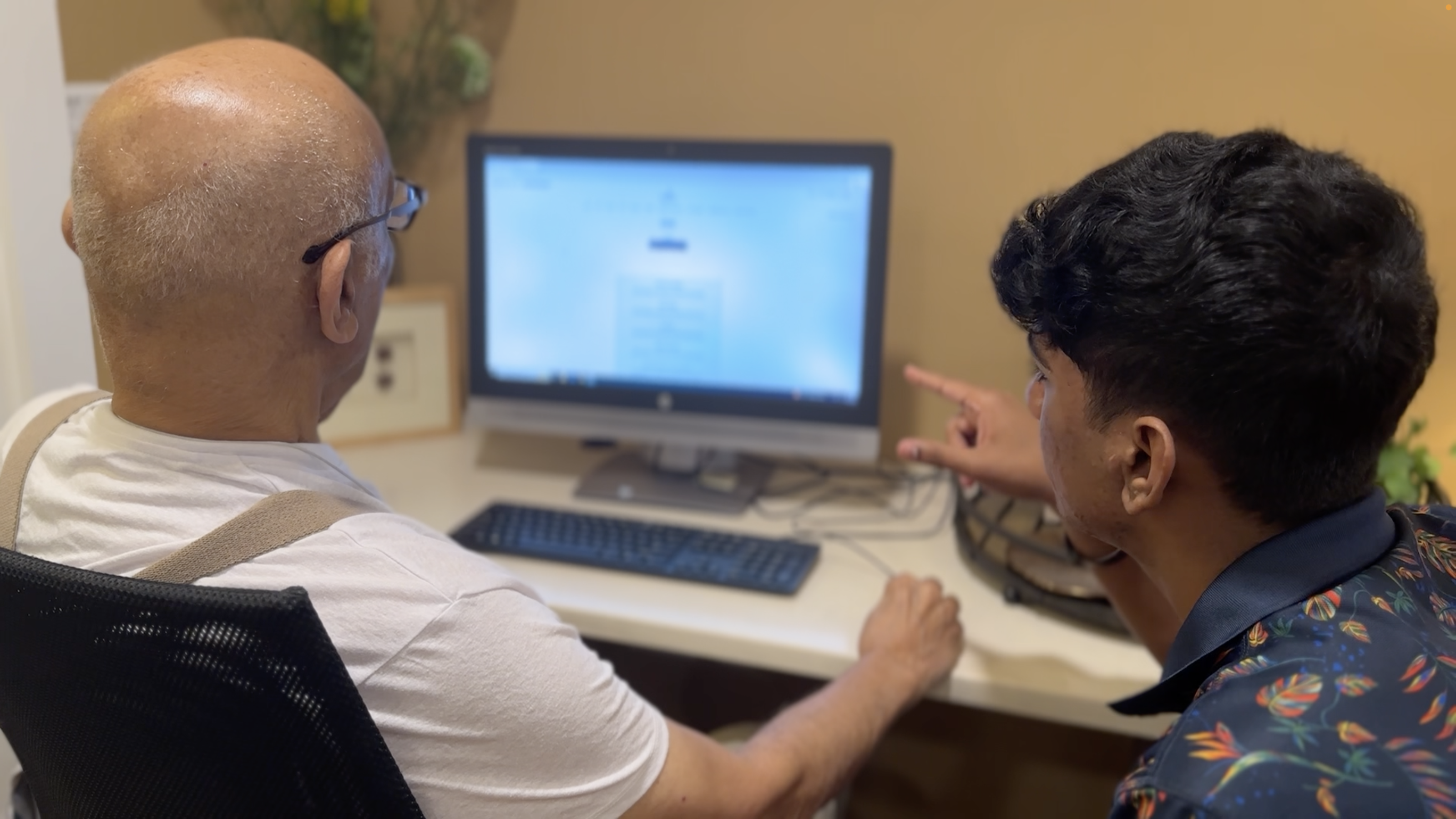 A NASTP volunteer helping a senior resident at a desktop computer