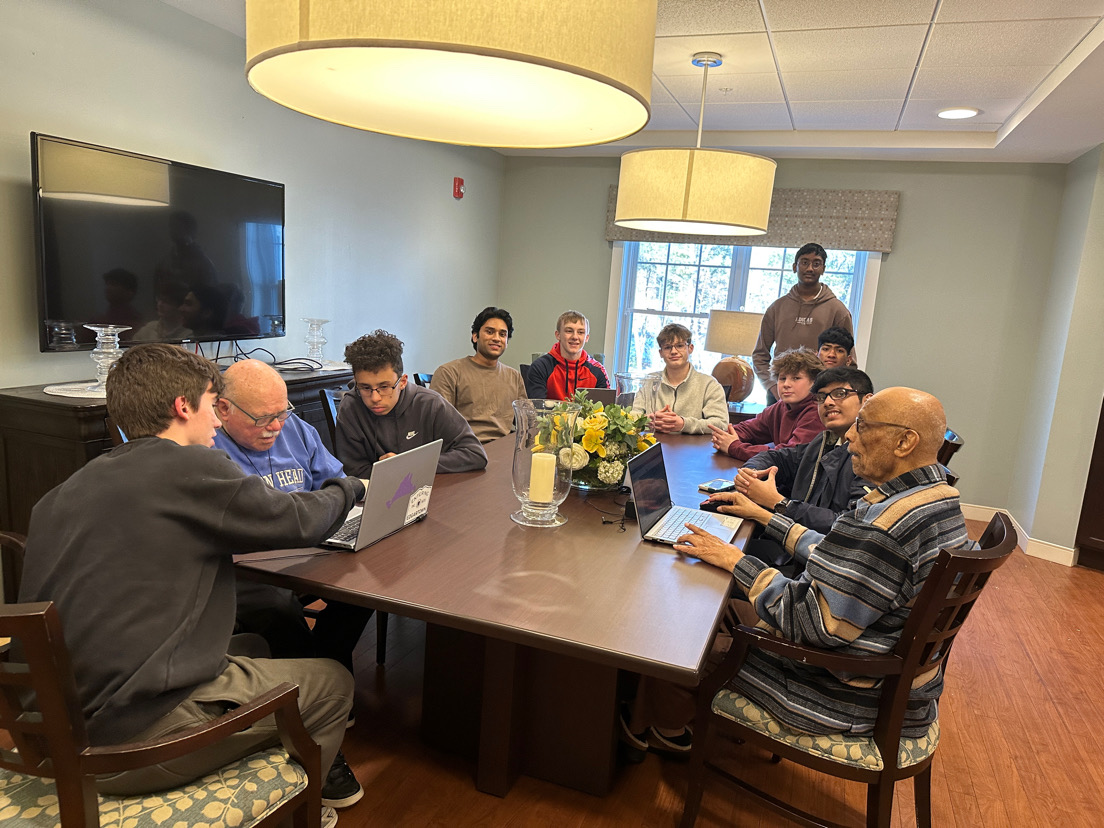 Student volunteers and seniors gathered around a table at a senior center