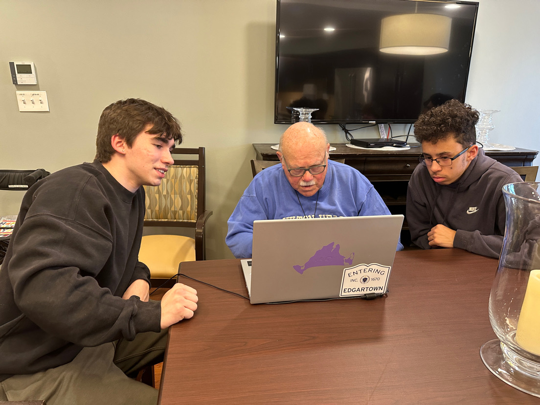 Student volunteers helping a senior one-on-one with a laptop